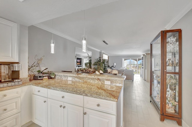 kitchen featuring decorative light fixtures, ornamental molding, open floor plan, white cabinets, and a peninsula