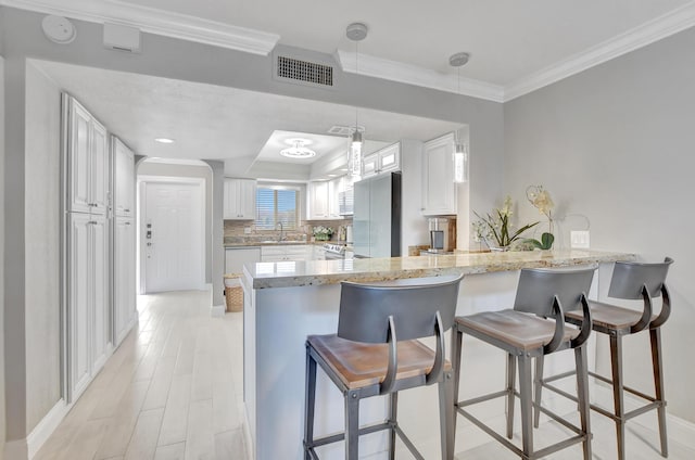 kitchen featuring a peninsula, visible vents, and white cabinets