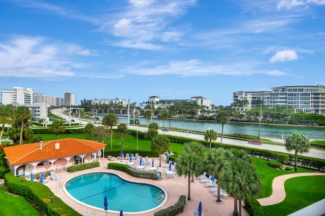 community pool with a water view, a patio, and a city view