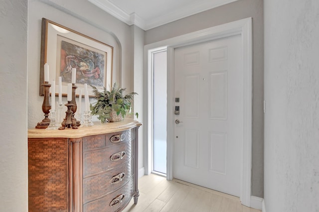 foyer with ornamental molding and light wood-style floors