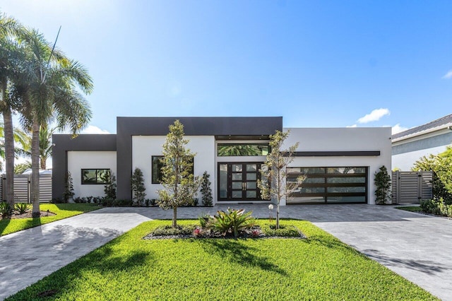 contemporary home with a garage, a front yard, decorative driveway, and stucco siding