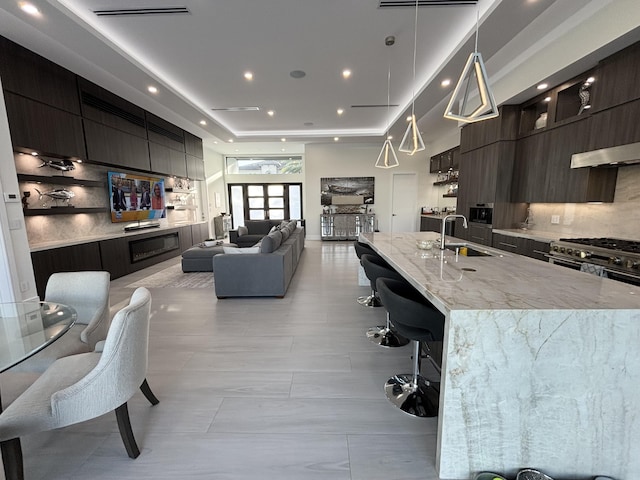 kitchen featuring a sink, open floor plan, tasteful backsplash, modern cabinets, and a kitchen bar