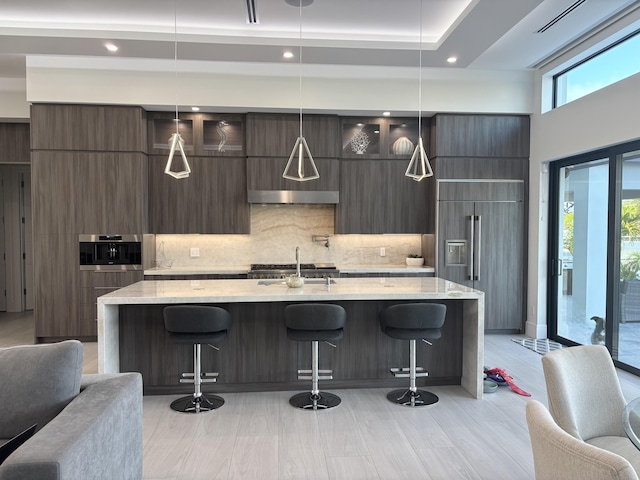 kitchen with modern cabinets, decorative backsplash, stainless steel oven, a sink, and paneled built in refrigerator