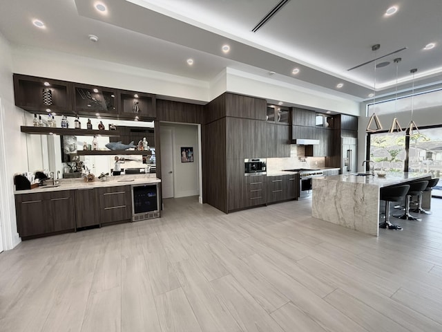 kitchen featuring dark brown cabinetry, beverage cooler, stainless steel range, modern cabinets, and glass insert cabinets