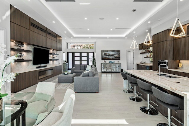 living area featuring a high ceiling, a tray ceiling, indoor wet bar, and recessed lighting