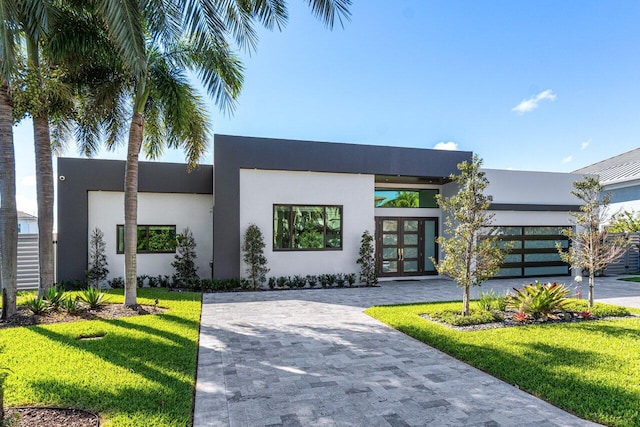 view of front facade with a front yard, decorative driveway, an attached garage, and stucco siding