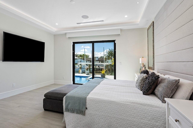 bedroom with light wood-type flooring, access to outside, baseboards, and a raised ceiling