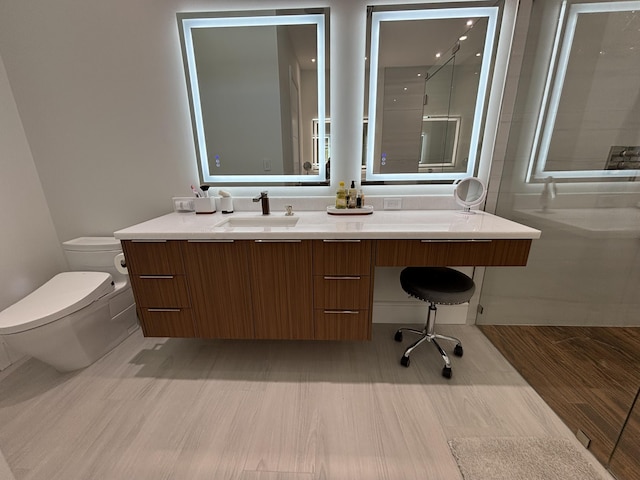 bathroom featuring toilet, a walk in shower, and vanity