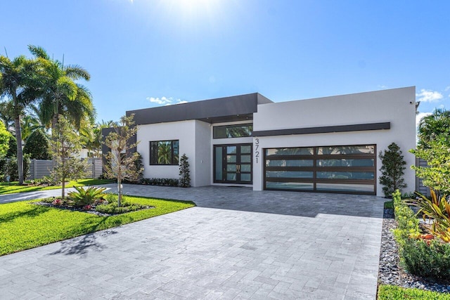 view of front facade featuring decorative driveway, an attached garage, and stucco siding