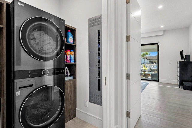 washroom with laundry area, beverage cooler, baseboards, stacked washer / drying machine, and wood finished floors