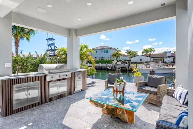 view of patio with a water view, grilling area, an outdoor kitchen, an outdoor hangout area, and a sink