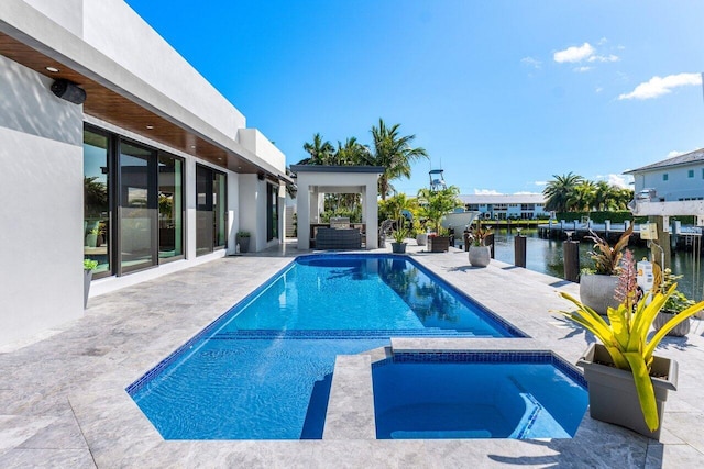 view of swimming pool with a patio area, a pool with connected hot tub, and a water view