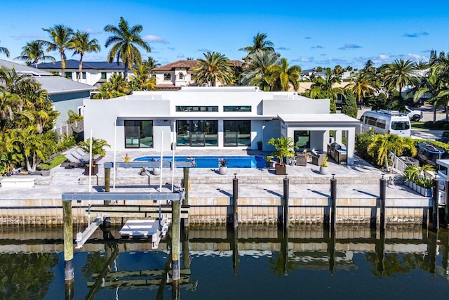 rear view of house with a patio, a water view, fence private yard, and stucco siding