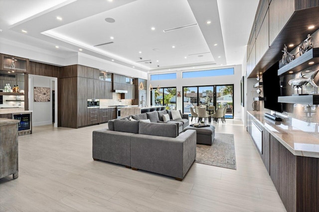 living area with a tray ceiling, a dry bar, recessed lighting, a towering ceiling, and beverage cooler