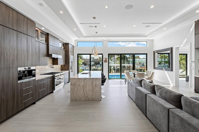 kitchen with open floor plan, modern cabinets, a center island with sink, and stainless steel stove