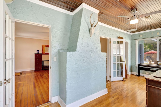 interior space with baseboards, a textured wall, wooden ceiling, ornamental molding, and wood finished floors