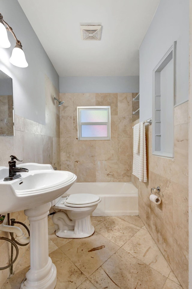 bathroom featuring toilet, visible vents, tub / shower combination, and tile walls