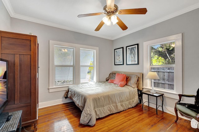 bedroom with a ceiling fan, crown molding, baseboards, and hardwood / wood-style floors