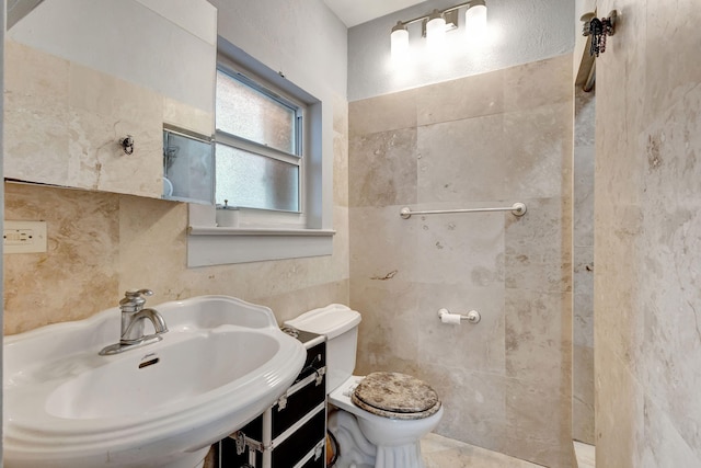 bathroom featuring a sink, toilet, and tile walls