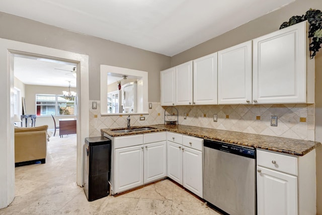 kitchen featuring tasteful backsplash, white cabinets, stainless steel dishwasher, a chandelier, and a sink