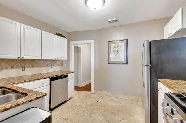 kitchen with light stone countertops, visible vents, white cabinets, appliances with stainless steel finishes, and decorative backsplash