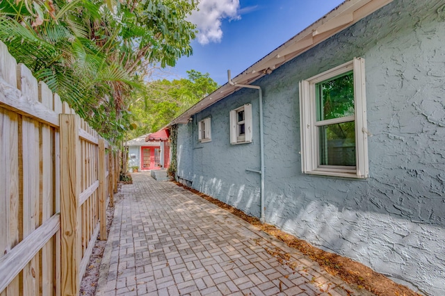 view of property exterior with a patio area, fence, and stucco siding