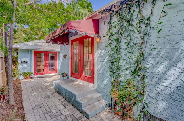 view of exterior entry featuring french doors and stucco siding