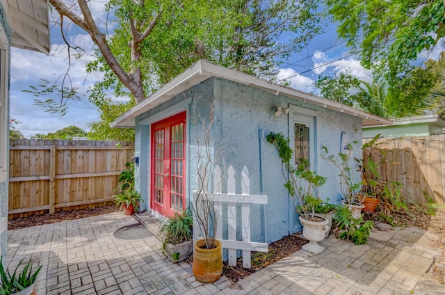 view of outdoor structure featuring a fenced backyard, french doors, and an outbuilding