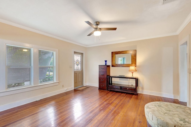 interior space with ornamental molding, wood-type flooring, ceiling fan, and baseboards