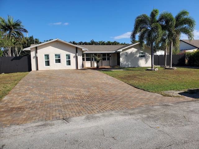 single story home featuring decorative driveway, fence, a front lawn, and stucco siding