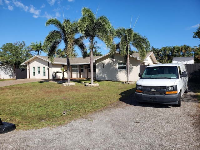 single story home featuring a front lawn, fence, and stucco siding