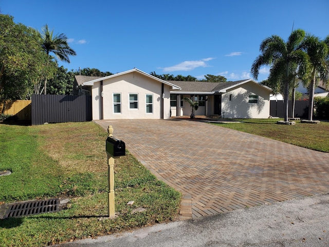 ranch-style home featuring a front yard, decorative driveway, fence, and stucco siding