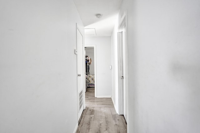 corridor with light wood-type flooring and baseboards