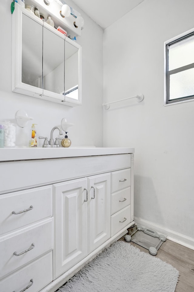 bathroom featuring baseboards, wood finished floors, and vanity