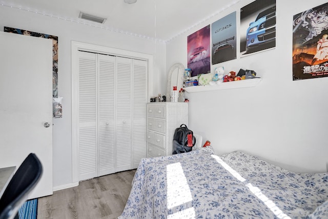 bedroom with a closet, visible vents, and wood finished floors