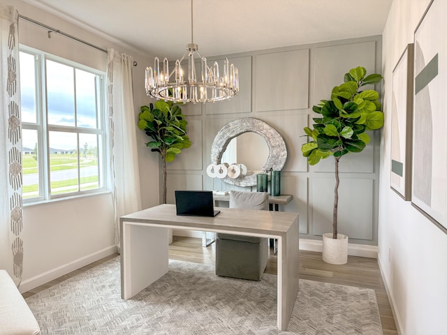 office area with baseboards, a chandelier, a decorative wall, and wood finished floors