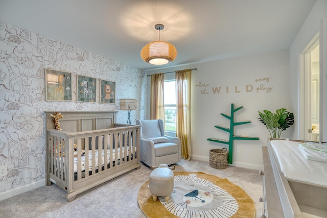 bedroom featuring a crib, baseboards, and wallpapered walls