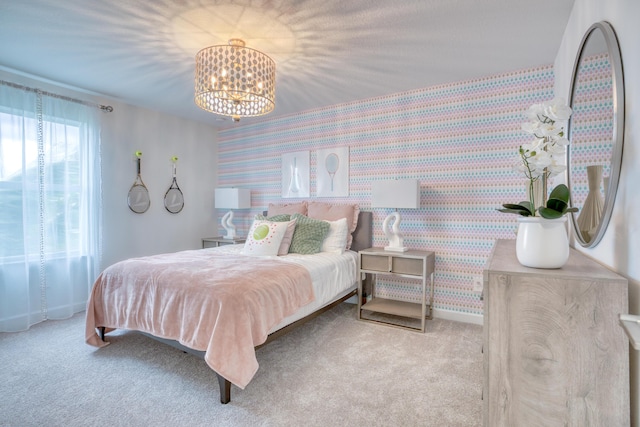 bedroom featuring carpet floors, an inviting chandelier, an accent wall, baseboards, and wallpapered walls