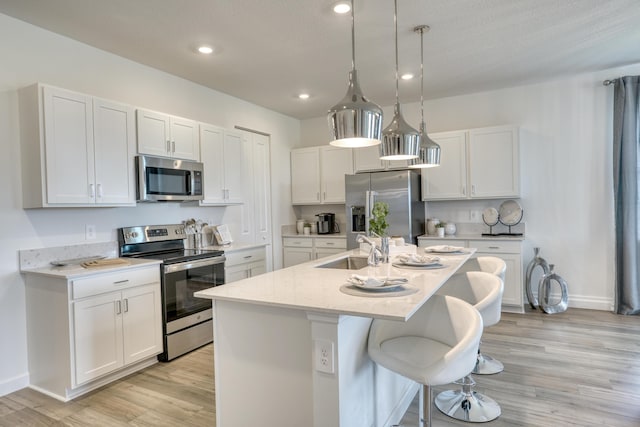 kitchen with stainless steel appliances, a sink, a kitchen island with sink, and white cabinets