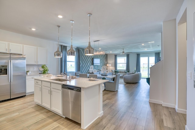 kitchen featuring light wood-type flooring, white cabinets, stainless steel appliances, and a sink