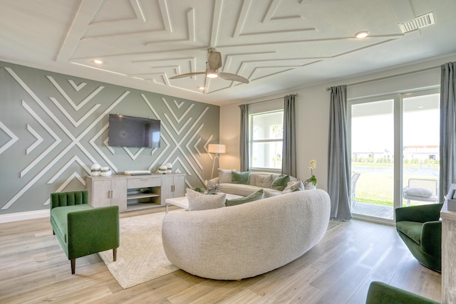 living area featuring plenty of natural light, light wood-style flooring, an accent wall, and visible vents