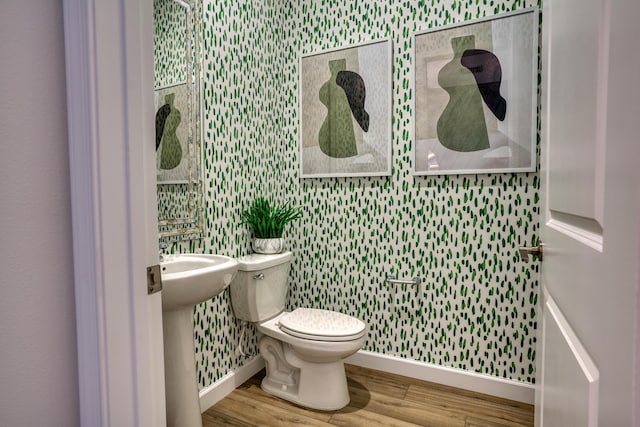 bathroom with toilet, baseboards, and wood finished floors