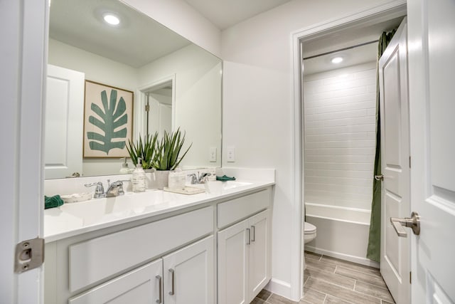 bathroom featuring wood tiled floor, a sink, toilet, and double vanity