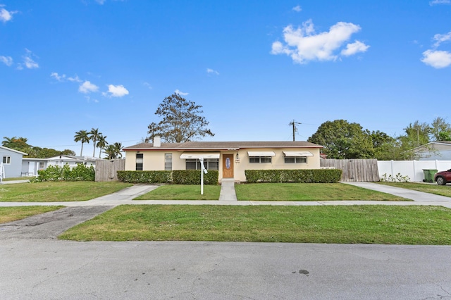 ranch-style home with a front yard, fence, and stucco siding