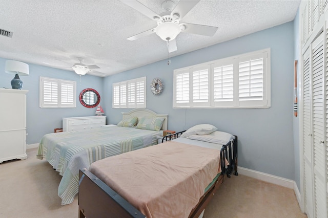 bedroom with a textured ceiling, ceiling fan, visible vents, baseboards, and carpet