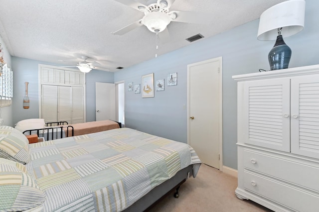 bedroom featuring visible vents, a ceiling fan, light colored carpet, a textured ceiling, and a closet