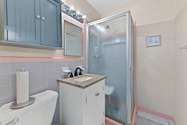 full bathroom with toilet, a shower stall, tile walls, and vanity