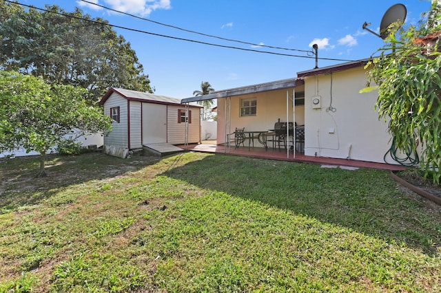 rear view of property featuring an outbuilding, a yard, a storage shed, and a patio