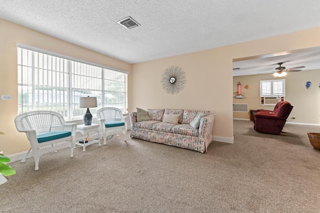 carpeted living room featuring a healthy amount of sunlight, visible vents, and a textured ceiling