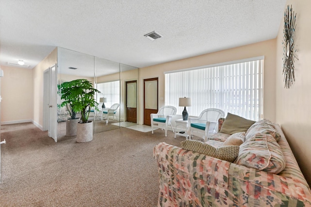 carpeted living area with visible vents, a textured ceiling, and baseboards